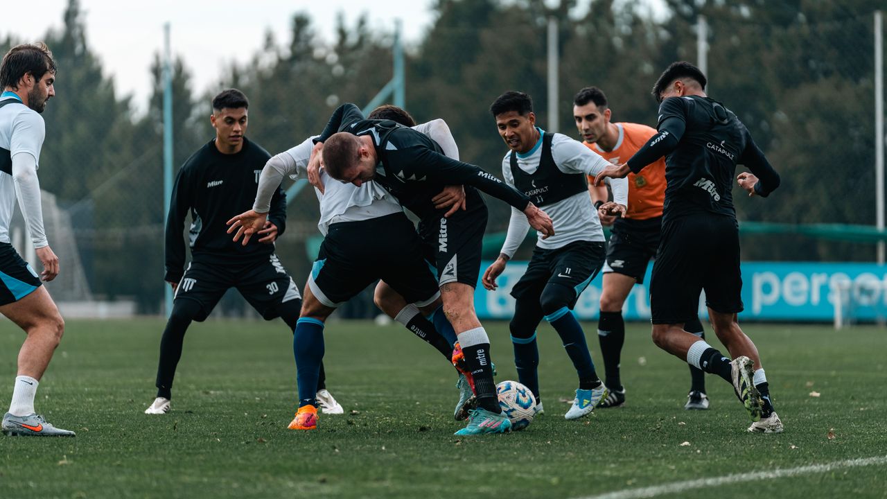 Intense soccer practice with team players competing for the ball on a green field.