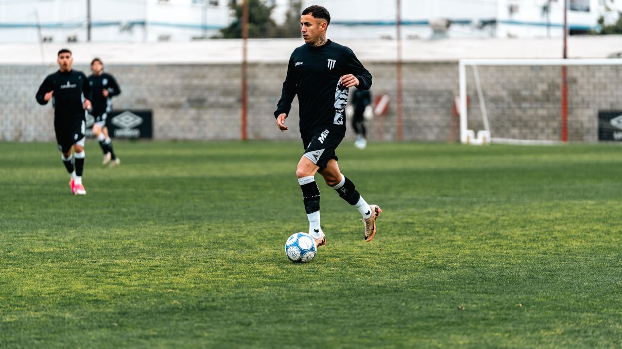 Athletes in black uniforms practicing soccer on a field.